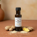 Sesame Ginger White Balsamic Vinegar bottle with ginger root and sesame seeds on terracotta surface